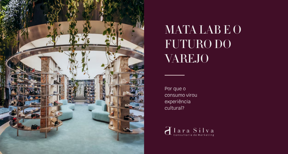 Interior da loja Mata Lab, um espaço moderno com conceito biofílico, onde estantes circulares exibem diversos modelos de calçados no centro do ambiente. Acima delas, uma estrutura metálica suspensa sustenta plantas pendentes e vegetação abundante. O espaço possui grandes janelas, iluminação natural, poltronas em tons claros e prateleiras com roupas nas laterais, criando uma atmosfera sofisticada e integrada à natureza.